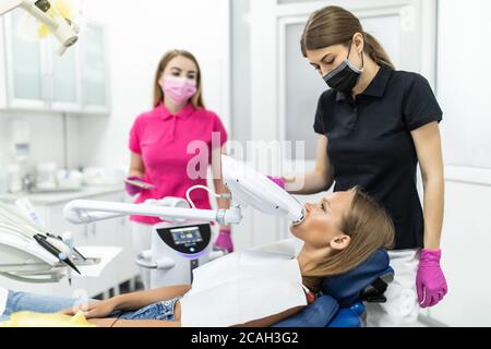 Lampe de blanchiment des dents ultravioleta. La fille à la réception chez le dentiste pour le blanchiment des dents. Banque D'Images