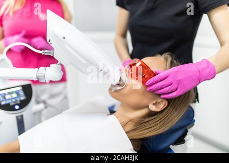 Lampe de blanchiment des dents ultravioleta. La fille à la réception chez le dentiste pour le blanchiment des dents. Banque D'Images