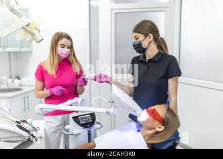 Lampe de blanchiment des dents ultravioleta. La fille à la réception chez le dentiste pour le blanchiment des dents. Banque D'Images