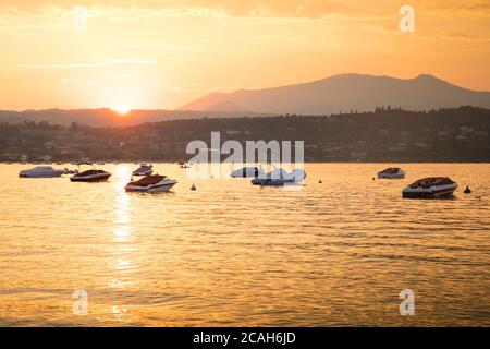 Vue sur le lac avec des bateaux fixes au coucher du soleil à Manerba del Garda, Italie. Banque D'Images