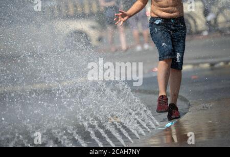 Munich, Allemagne. 07e août 2020. Un garçon joue avec l'eau d'un puits au Stachus. Credit: Sven Hoppe/dpa/Alay Live News Banque D'Images