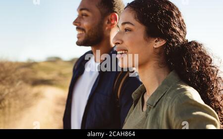 Gros plan d'un couple souriant debout à l'extérieur, en admirant la nature. Photo d'un couple en vacances debout à l'extérieur, avec vue sur l'extérieur. Banque D'Images