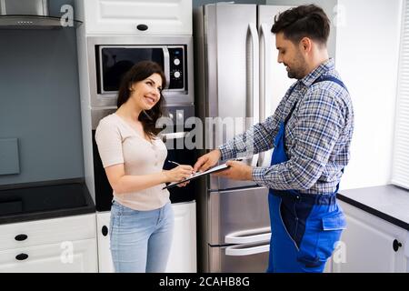 Bonne cliente femme signant la facture du plombier en interne Banque D'Images