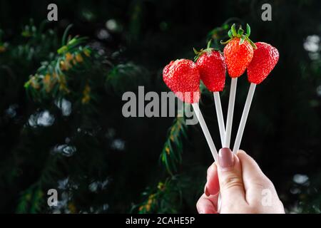 Bouquet de petits fruits comestibles alternative dans la main d'un homme ou femme, anniversaire, Saint-Valentin, vacances, close-up. Des fraises entières sur sk en bois Banque D'Images