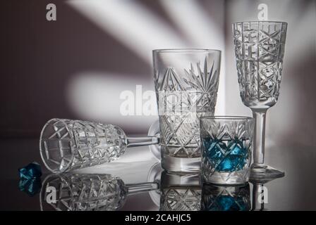 Verres en cristal sur une surface miroir et un magnifique fond peint avec lumière Banque D'Images