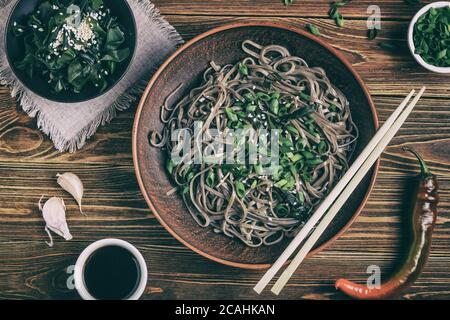 Encore la vie avec vue sur les nouilles soba japonaises traditionnelles avec du nori (algues comestibles) et de la sauce soja, sur une surface en bois Banque D'Images