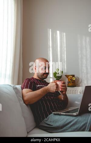 les jeunes ont un bon moment à la maison. écouter de la musique, boire du café et du thé. Adolescent au repos qui court avec une tablette et un leptop dans les mains. Banque D'Images