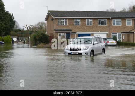 Une voiture traversant les eaux d'inondation sur Aymer Drive, Egham Hythe, Surrey, après que la Tamise l'ait brisée, Aymer Drive, Egham Hythe, Surrey, Royaume-Uni. 14 févr. 2014 Banque D'Images