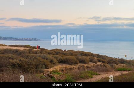 ÉTATS-UNIS. 06e août 2020. Une femme portant une robe rose et un masque facial marche sur les falaises après le coucher du soleil à Torrey Pines Gliderport à la Jolla, Californie, le jeudi 6 août 2020. (Photo de Rishi Deka/Sipa USA) crédit: SIPA USA/Alay Live News Banque D'Images