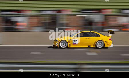 Une photo panoramique d'une voiture de course jaune qui fait le circuit d'une piste. Banque D'Images