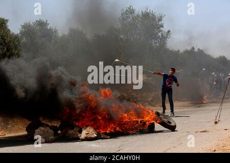 Ramallah, Turmus Aya près de la ville de Ramallah en Cisjordanie. 7 août 2020. Un manifestant palestinien lance des pierres contre la police frontalière israélienne et les soldats lors d'affrontements à la suite d'une protestation contre l'expansion des colonies juives et le plan d'annexion par Israël, dans le village de Turmus Aya, près de la ville de Ramallah, en Cisjordanie, le 7 août 2020. Credit: Ayman Nobani/Xinhua/Alamy Live News Banque D'Images