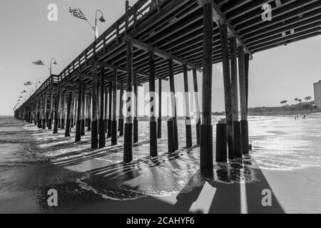 Vue en noir et blanc sous la jetée en bois historique de la plage de Ventura, en Californie du Sud. Banque D'Images