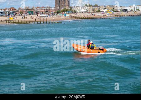 Un petit bateau de sauvetage semi-rigide et gonflable RNLI patrouilant sur la mer de Littlehampton Beach lors d'une journée chargée en août. Banque D'Images