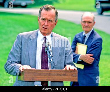 Dans ce dossier photo, le président des États-Unis George H.W. Bush parle aux journalistes de l'invasion du Koweït par l'Irak avant de quitter la Maison Blanche pour la retraite présidentielle à Camp David le 3 août 1990. Brent Scowcroft, conseiller en sécurité nationale, regarde de Right.Credit: Ron Sachs/CNP | usage dans le monde entier Banque D'Images