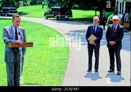 Dans ce dossier photo, le président des États-Unis George H.W. Bush parle aux journalistes de l'invasion du Koweït par l'Irak avant de quitter la Maison Blanche pour la retraite présidentielle à Camp David le 3 août 1990. À droite se trouvent le conseiller à la sécurité nationale Brent Scowcroft et le secrétaire de presse de la Maison Blanche Marlin Fitzwater (port de chapeau).Credit: Ron Sachs/CNP | usage dans le monde entier Banque D'Images