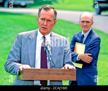 Dans ce dossier photo, le président des États-Unis George H.W. Bush parle aux journalistes de l'invasion du Koweït par l'Irak avant de quitter la Maison Blanche pour la retraite présidentielle à Camp David le 3 août 1990. Brent Scowcroft, conseiller en sécurité nationale, regarde de droite.Credit: Ron Sachs / CNP / MediaPunch Banque D'Images