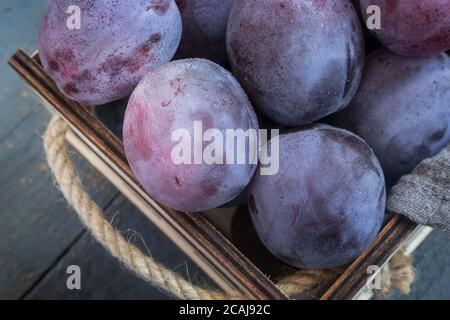 Grands prunes mûres dans un récipient sur la table Banque D'Images