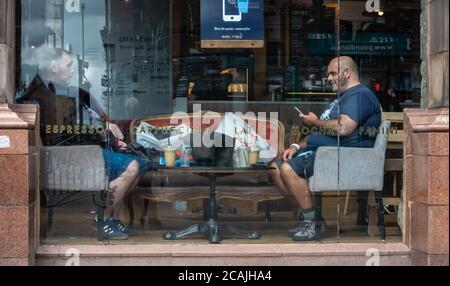 Glasgow, Écosse, Royaume-Uni. 7 août 2020. Météo Royaume-Uni. Clients dans la fenêtre de Caffe Nero sur Trongate ayant un café. Credit: SKULLY/Alay Live News Banque D'Images