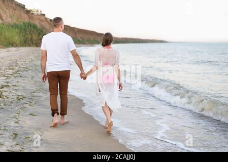 Un jeune couple marche les mains le long de la côte. Vue arrière Banque D'Images