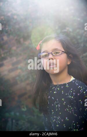 fille de 5 ans avec des lunettes regardant quizziquement à l'appareil photo Banque D'Images