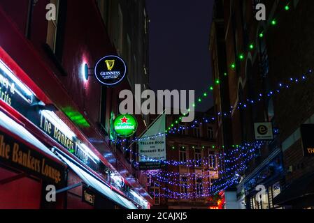 Dublin, Irlande - 30 décembre 2019 : enseignes au néon annonçant la bière Guinness et Heineken d'un pub irlandais et décoration de Noël sur une rue à Dublin, Banque D'Images