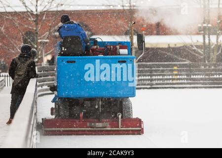 préparation de glace à la patinoire entre les séances par temps neigeux. Glace polie prête pour le match. Vue arrière de la machine d'entretien de la glace Banque D'Images