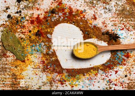 Ensemble d'épices sur fond de bois blanc. Composition du condiment en forme de coeur. Concept de l'art alimentaire. Cuillère en bois avec poudre de curcuma, sel de mer, étoile anis, feuille de Laurier et assaisonnement épars Banque D'Images