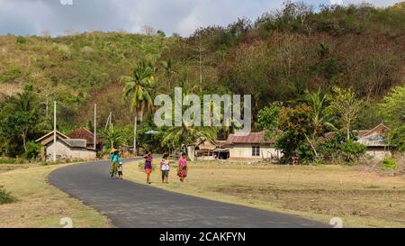 Lombok, Indonésie - 11 octobre 2017 : une famille marchant le long de la route dans un village près de la plage de Mawun, près de Kuta, Lombok, Indonésie Banque D'Images