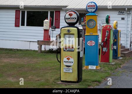 Collection de pompes à gaz d'époque et de panneaux sur pelouse résidentielle, New Hampshire, États-Unis Banque D'Images