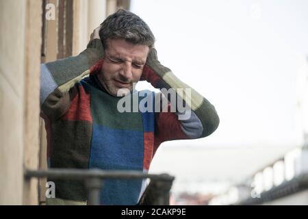 style de vie urbain portrait émotionnel de jeune homme attrayant et déprimé à la maison balcon penché bouleversé se sentant désespéré souffrant de problème de dépression Banque D'Images