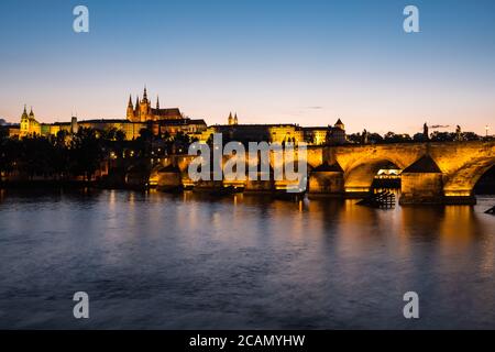 Pont Charles illuminé à Prague à Dusk en traversant la Vltava Avec la cathédrale Saint-Vitus et le château de Prague Banque D'Images