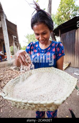 Haikesa / Indonésie - 10 août 2018 : femme qui filtre du riz avec tamis dans un village rural pauvre Banque D'Images