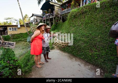 Bali / Indonésie - 15 août 2018 : touriste occidental avec chapeau traditionnel prenant des photos avec un fermier qui charge pour prendre des photos avec des touristes Banque D'Images