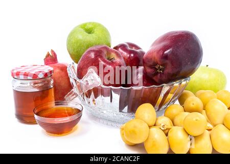 Rosh Hashanah, nouvel an juif, symboles traditionnels, miel dans un pot en verre, grenades, dattes, pommes rouges et vertes. Isolé sur UN arrière-plan blanc Banque D'Images