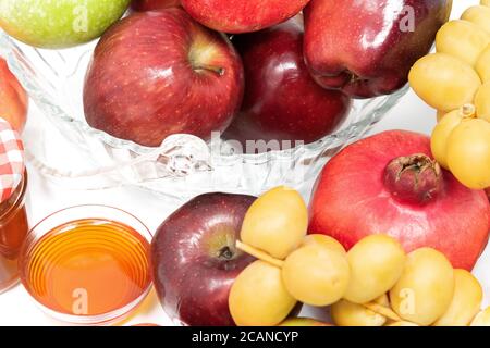 Rosh Hashanah, nouvel an juif, symboles traditionnels, miel dans un pot en verre, grenades, dattes, pommes rouges et vertes. Isolé sur UN arrière-plan blanc Banque D'Images