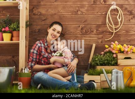 Une petite fille adorable aide sa mère à s'occuper des plantes. Mère et sa fille se sont engagées dans le jardinage dans la cour. Concept de printemps, nature et soins. Banque D'Images