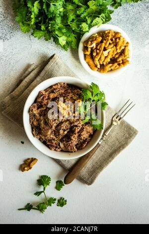 Plat traditionnel de haricots géorgiens - lobio aux noix, servi dans un bol moderne en céramique texturée sur fond de pierre avec espace pour les copies Banque D'Images
