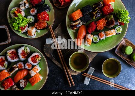 Sushi avec divers sashimis, petits pains à sushis et thé servis sur ardoise de pierre Banque D'Images