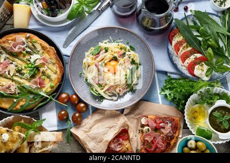 Appétissant cuisine italienne classique sur une table rustique en bois. Différents types de pizzas, pâtes, en-cas et careze. Des aliments sains faits maison. Vue de dessus, plate Banque D'Images