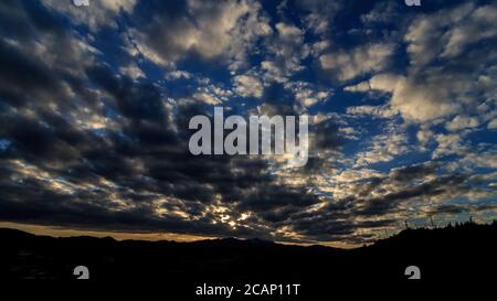 Des rayons du soleil traversent des nuages orageux à Larnaca, Chypre, au-dessus d'un petit village entouré de montagnes Banque D'Images