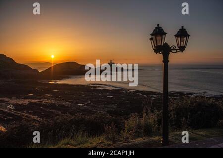 Mumbles, Swansea, Royaume-Uni. 8 août 2020. Le soleil se lève sur le phare de Mumbles près de Swansea ce matin, vu de l'extérieur du restaurant Castellamare au début d'une journée d'été du Royaume-Uni. Credit: Phil Rees/Alamy Live News Banque D'Images