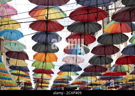 Un groupe de parapluie de différentes couleurs placé à côté de chaque autres au-dessus de la rue dans différentes couleurs et nuances Banque D'Images