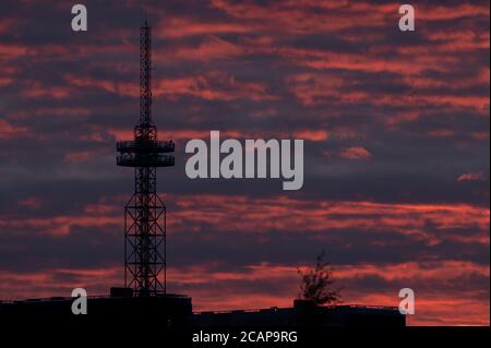 Helsinki / Finlande - 6 août 2020 : silhouette d'une grande tour de télécommunication / radiodiffusion contre un ciel rouge vif lors d'une soirée d'été trouble. Banque D'Images