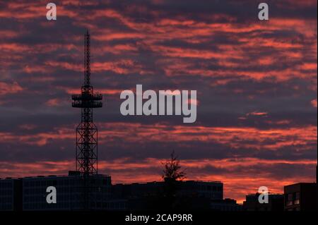 Helsinki / Finlande - 6 août 2020 : silhouette d'une grande tour de télécommunication / radiodiffusion contre un ciel rouge vif lors d'une soirée d'été trouble. Banque D'Images