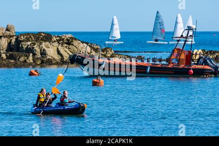 North Berwick, East Lothian, Écosse, 8 août 2020. Météo au Royaume-Uni : journée idéale pour les sports nautiques. Une chaude journée ensoleillée dans le Firth of Forth attire les gens à prendre à l'eau. Un groupe d'enfants s'amusent à pagayer dans un canoë gonflable dans West Bay avec des dinghies de voile comme East Lothian Yacht Club organise une course de club Banque D'Images