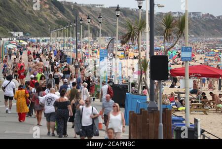 Les gens marchent le long du front de mer sur la plage de Boscombe à Dorset. Banque D'Images