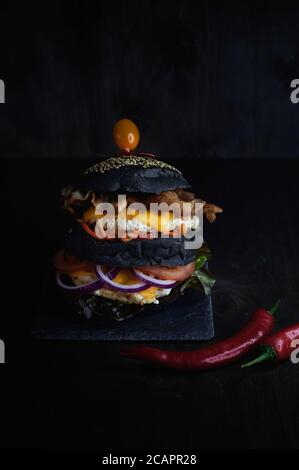 Délicieux hamburger sur fond sombre filmé verticalement Banque D'Images