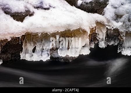 Glaces d'hiver au-dessus du cours d'eau. Eau gelée avec bulles et flocons de neige Banque D'Images