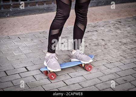 Skate en milieu urbain. Teen Girl est debout sur le pennyboard et essaie de garder l'équilibre. Banque D'Images