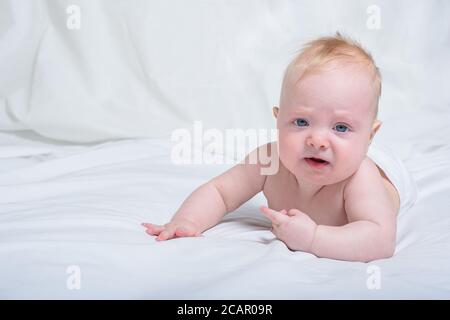 Bébé déplaisait sur son ventre. Arrière-plan blanc Banque D'Images